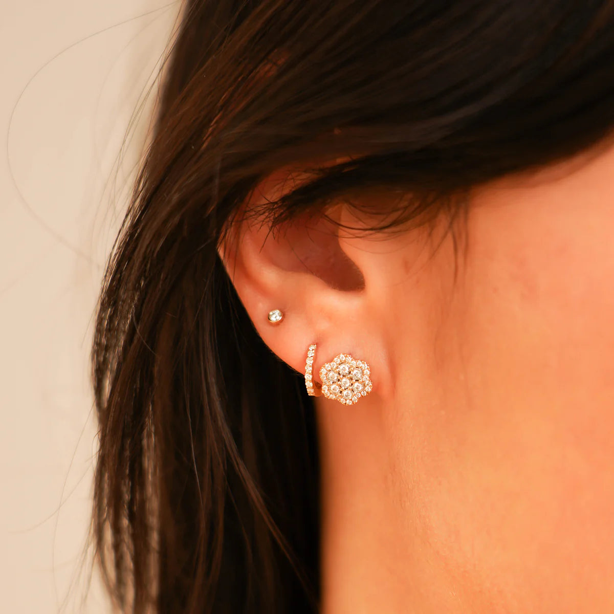 close up of Ava Bea Flower Studs in yellow Gold styled on an ear with other earrings
