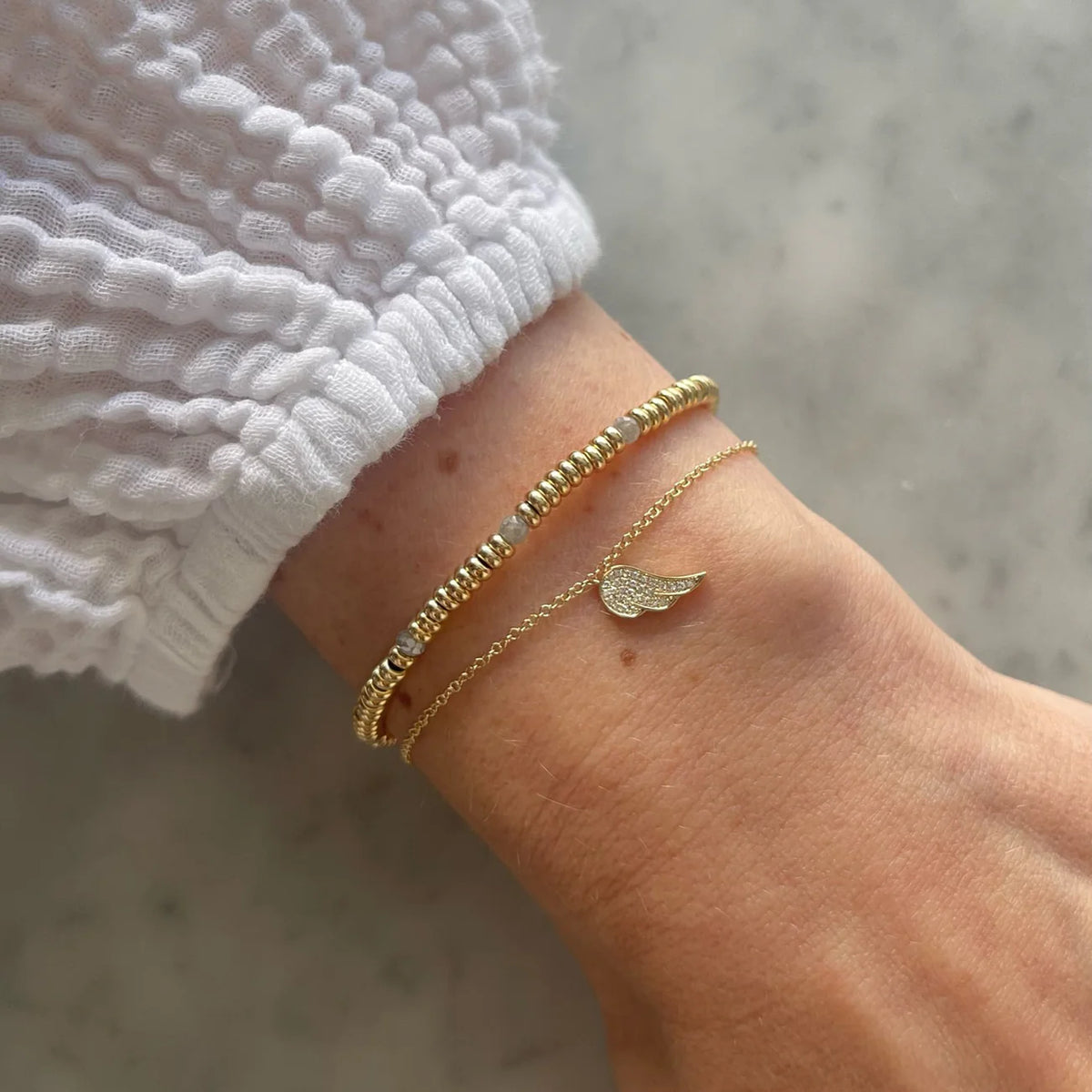 EF-Collection Birthstone Bead Bracelet In Diamond in yellow gold on models wrist with single angel wing bracelet