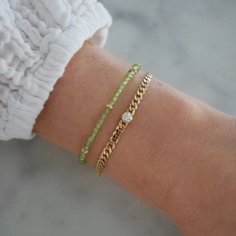 EF-Collection Birthstone Bead Bracelet In Peridot in yellow gold styled on models wrist with chain bracelet 
