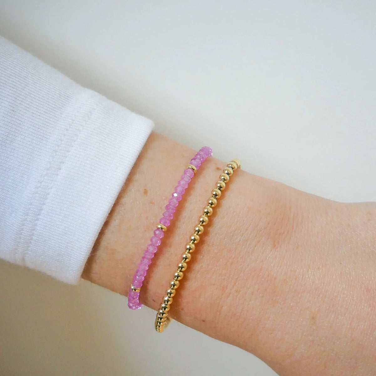EF-Collection Birthstone Bead Bracelet In Pink Sapphire in yellow gold styled on models wrist with bead bracelet 