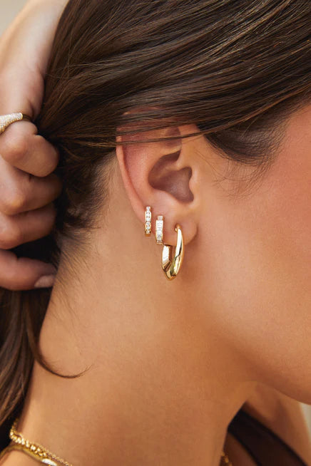 Close up of EF-Collection Channel Set Diamond Baguette Huggie Earrings in yellow gold on models ear