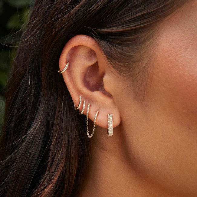 EF-Collection Diamond Double Mini Huggie Chain Earring in yellow gold on models ears stacked with different huggies. 