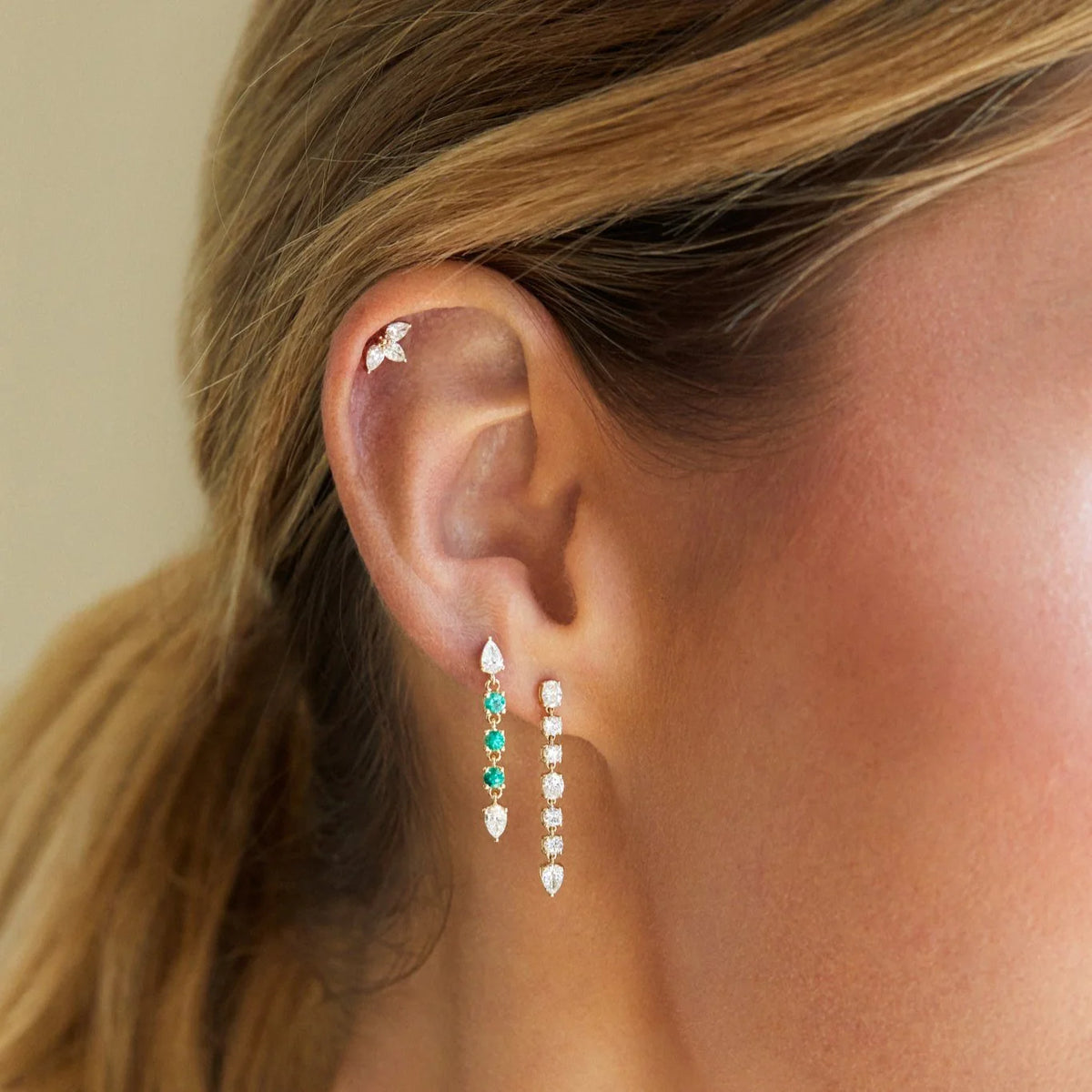 Close up of EF-Collection Diamond & Emerald Drop Stud Earrings in yellow gold on models ear with diamond drop stud earrings