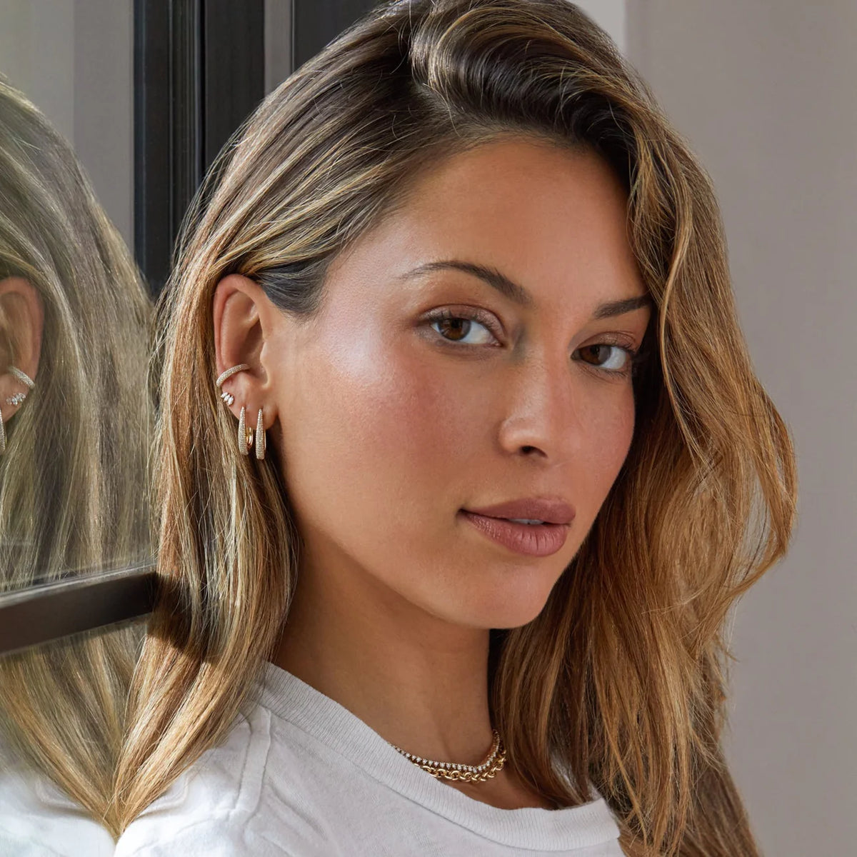 Shot of models face wearing EF-Collection Diamond Maeve Hoop Earrings in yellow gold 