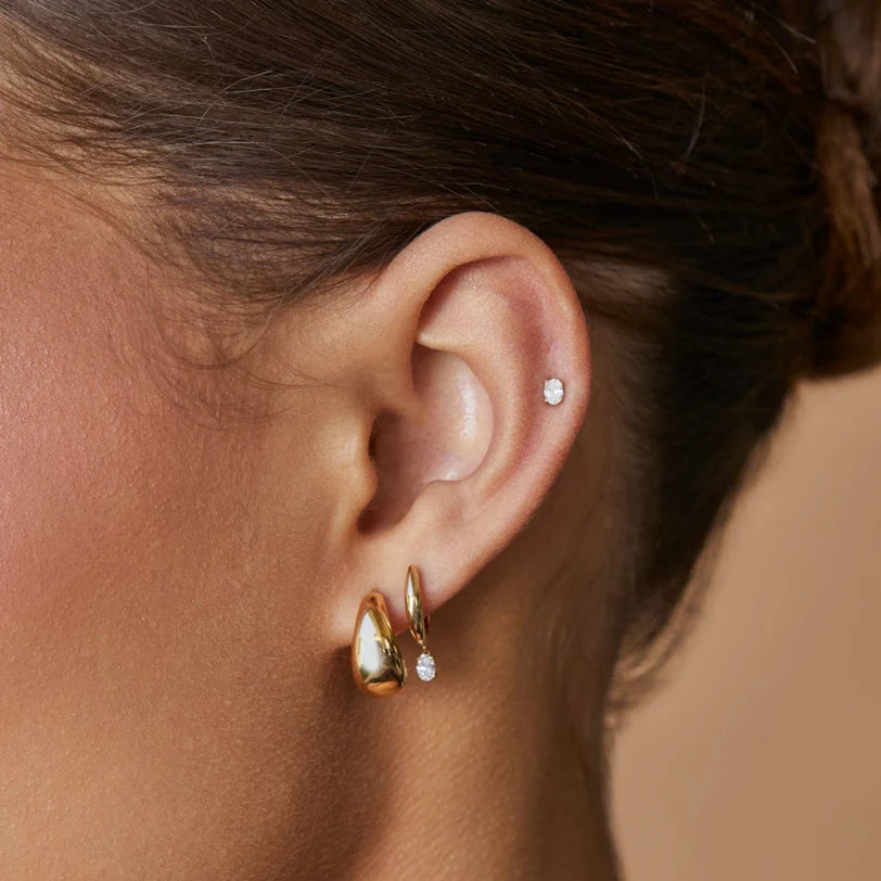 EF Collection Diamond Oval Drop Gold Dome Huggie Earring in yellow gold styled on models ear. 