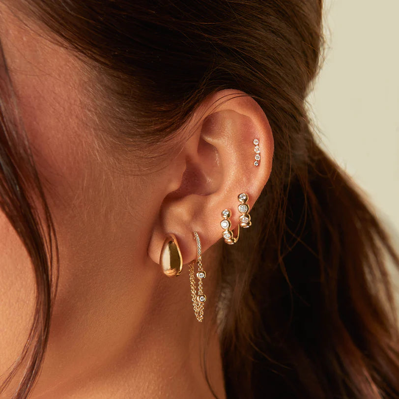 EF Collection Diamond Pillow Huggie Earrings in yellow gold styled on models ear. 