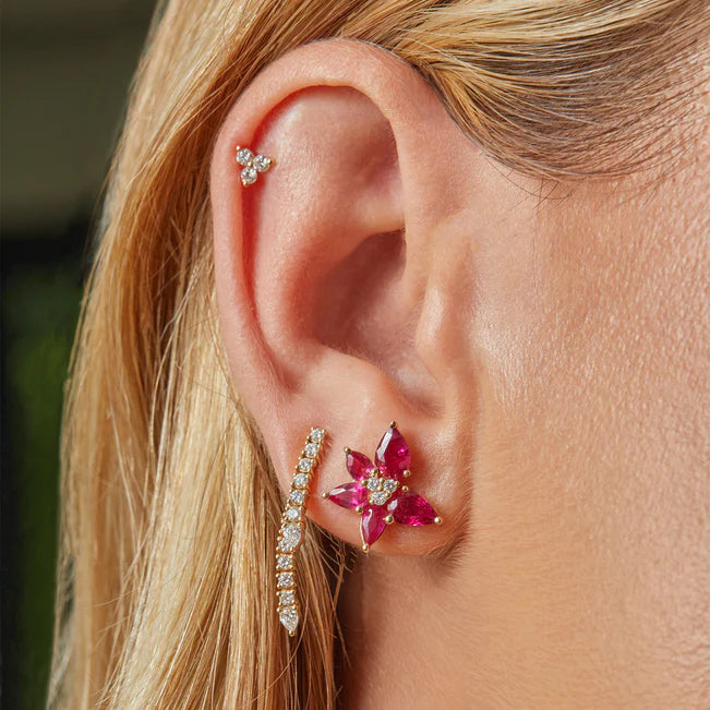 EF-Collection Diamond Teardrop Fringe Earring layered with a floral stud and a triple diamond piercing on models ear. 