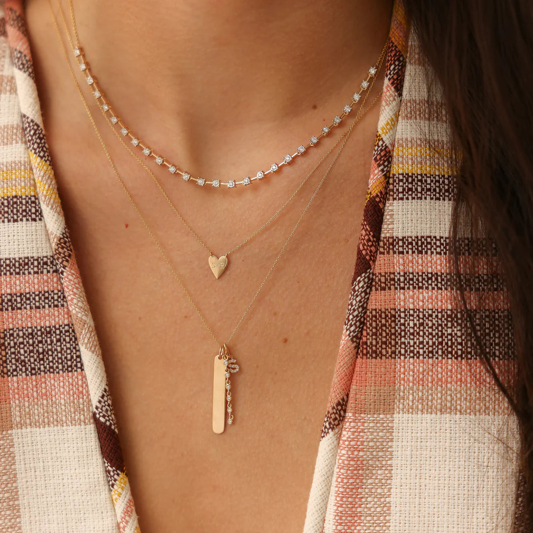 Dana Rebecca Designs DRD Diamond Initial Charm in yellow gold styled on models neck with yellow gold heart necklace 