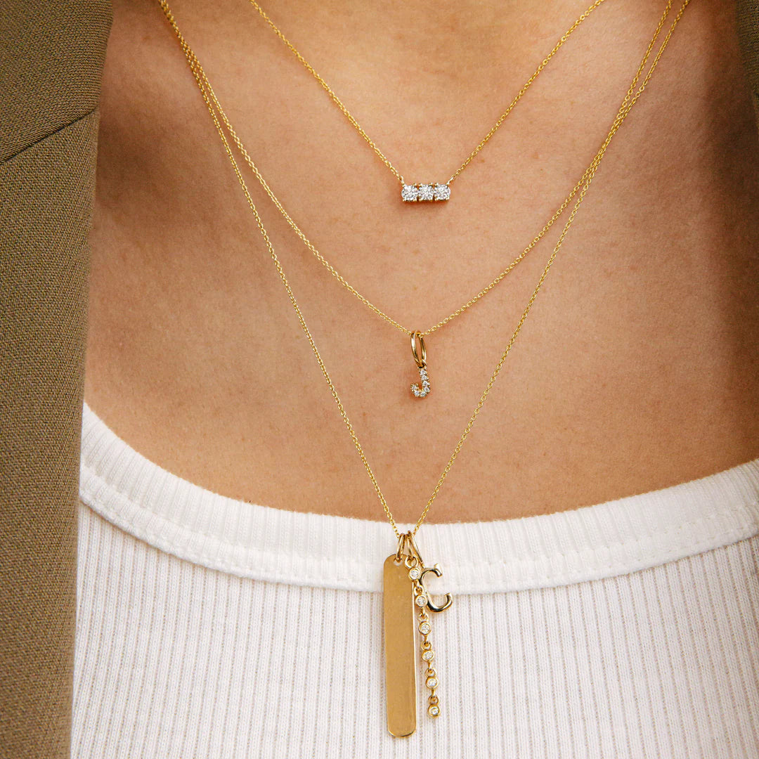 Dana Rebecca Designs DRD Diamond Initial Charm in yellow gold styled on models neck wearing a white tank top 