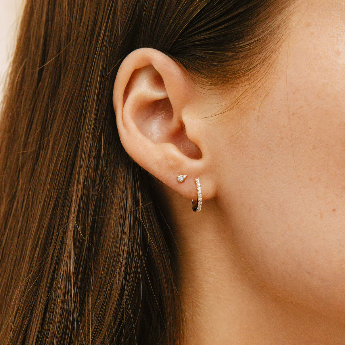 Dana Rebecca Designs DRD Medium Huggies in yellow gold styled on models ear with single diamond stud 