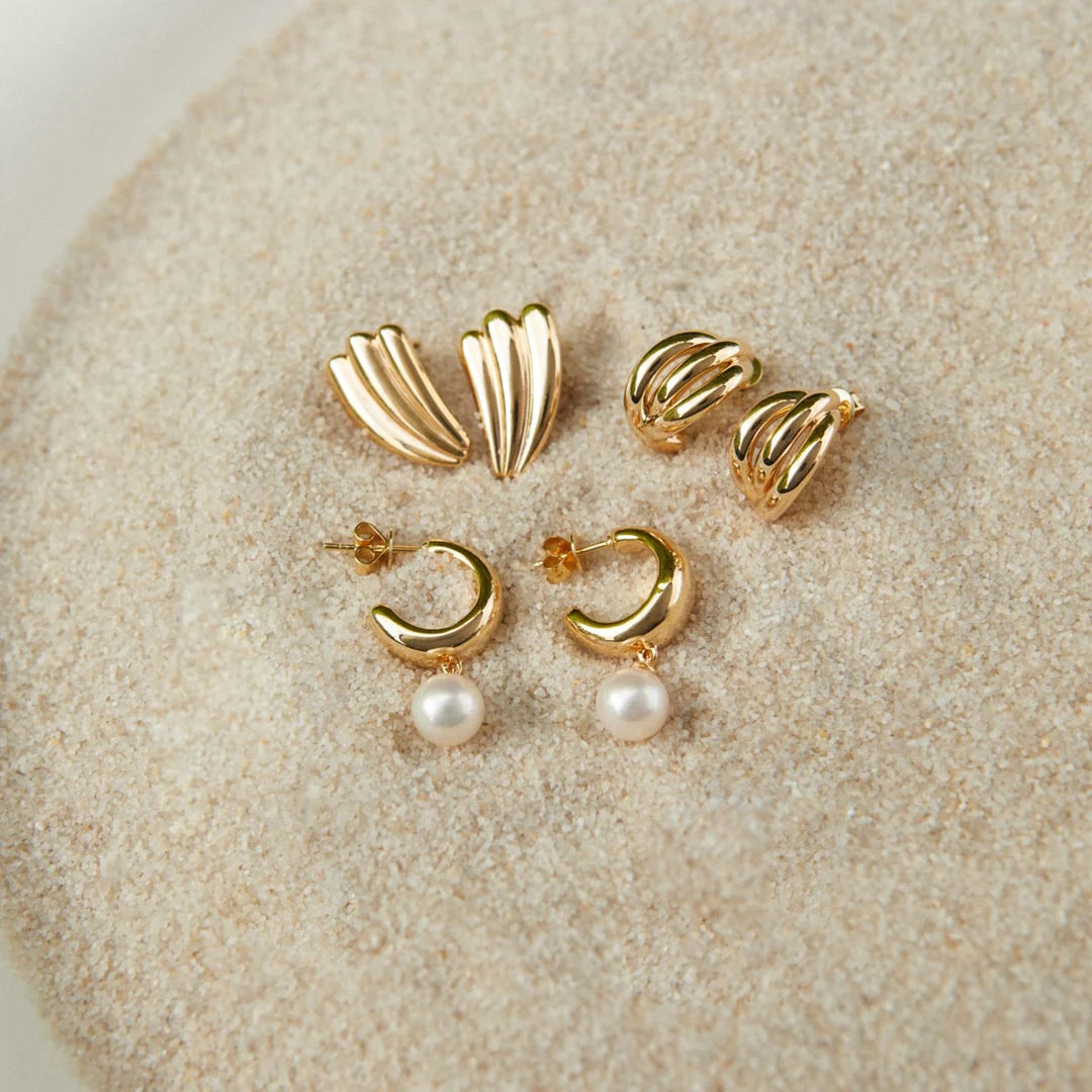 Set of EF Collection gold earrings with pearl accents on a beige surface