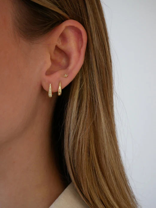 EF Collection Gold Mini Maeve Huggie Earrings in yellow gold on models ear stacked with a huggie and a small diamaond stud. 