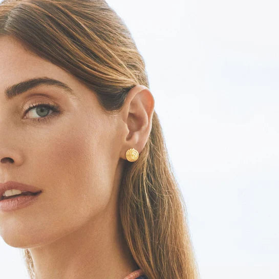 EF-Collection Gold Swirl Stud Earrings in yellow gold styled on models ear with a blurred background 
