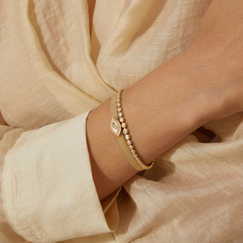 Product shot of EF-Collection Graduated Diamond Pillow Tennis Bracelet in yellow gold styled on models wrist wearing a yellow shirt 