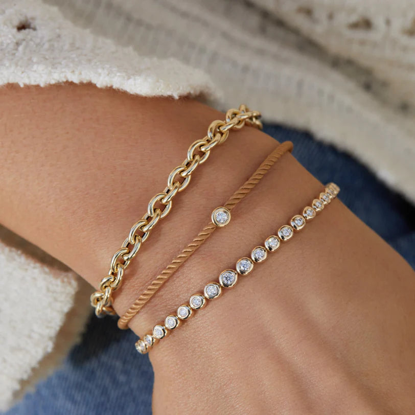 Product shot of EF-Collection Graduated Diamond Pillow Tennis Bracelet in yellow gold on models wrist with chain bracelet 