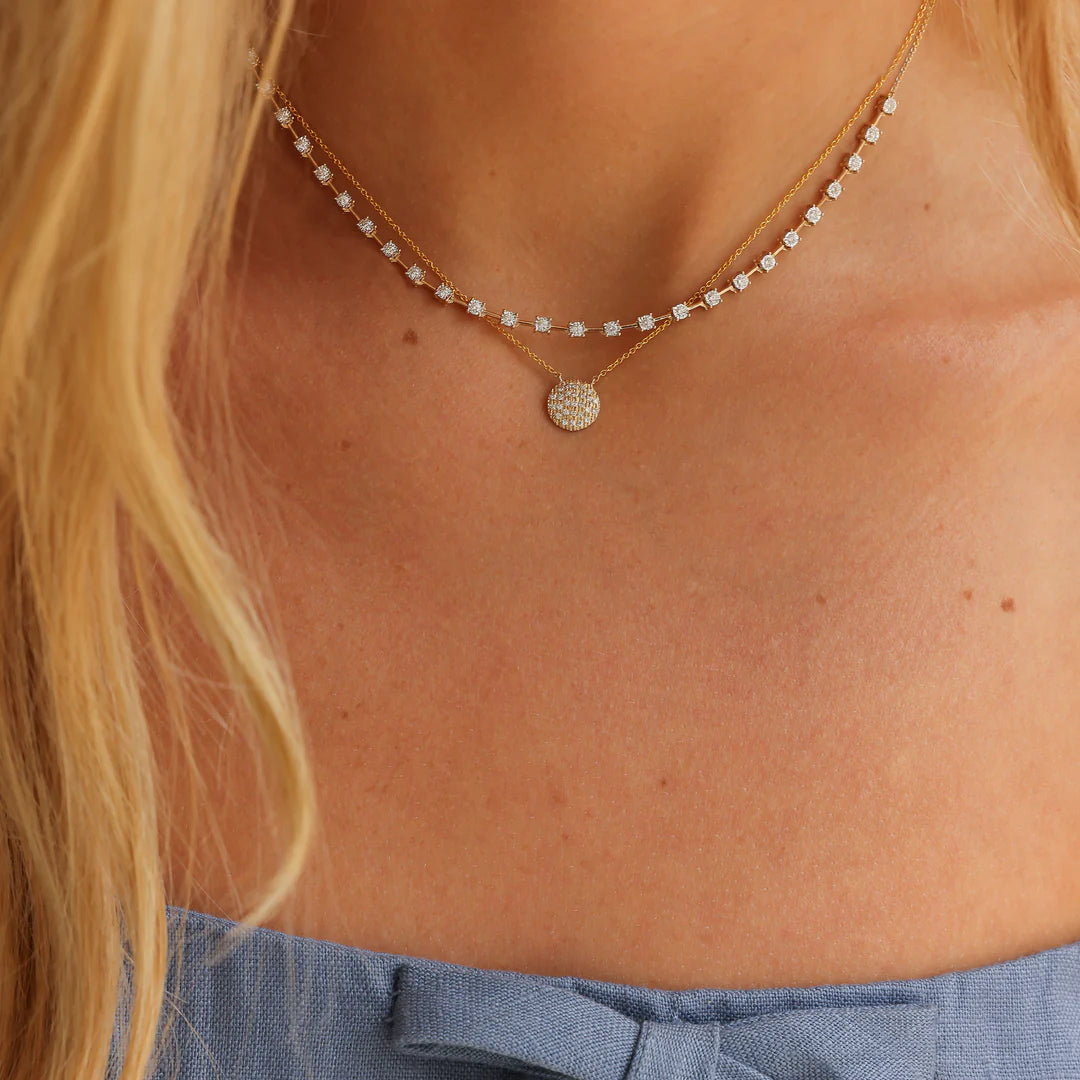 Close up of Dana Rebecca Designs Lauren Joy Medium Disc Necklace in yellow gold  layered on ava bea interval tennis necklace 