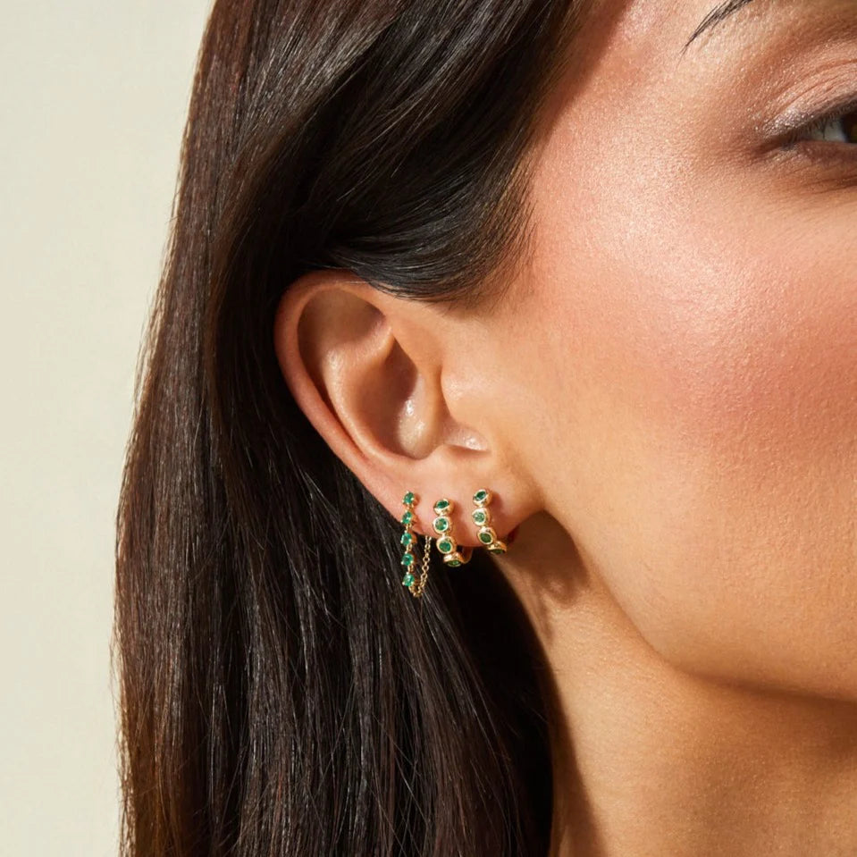 EF-Collection Multi Emerald Chain Stud Earrings in yellow gold stacked on models ear with two emerald huggies 