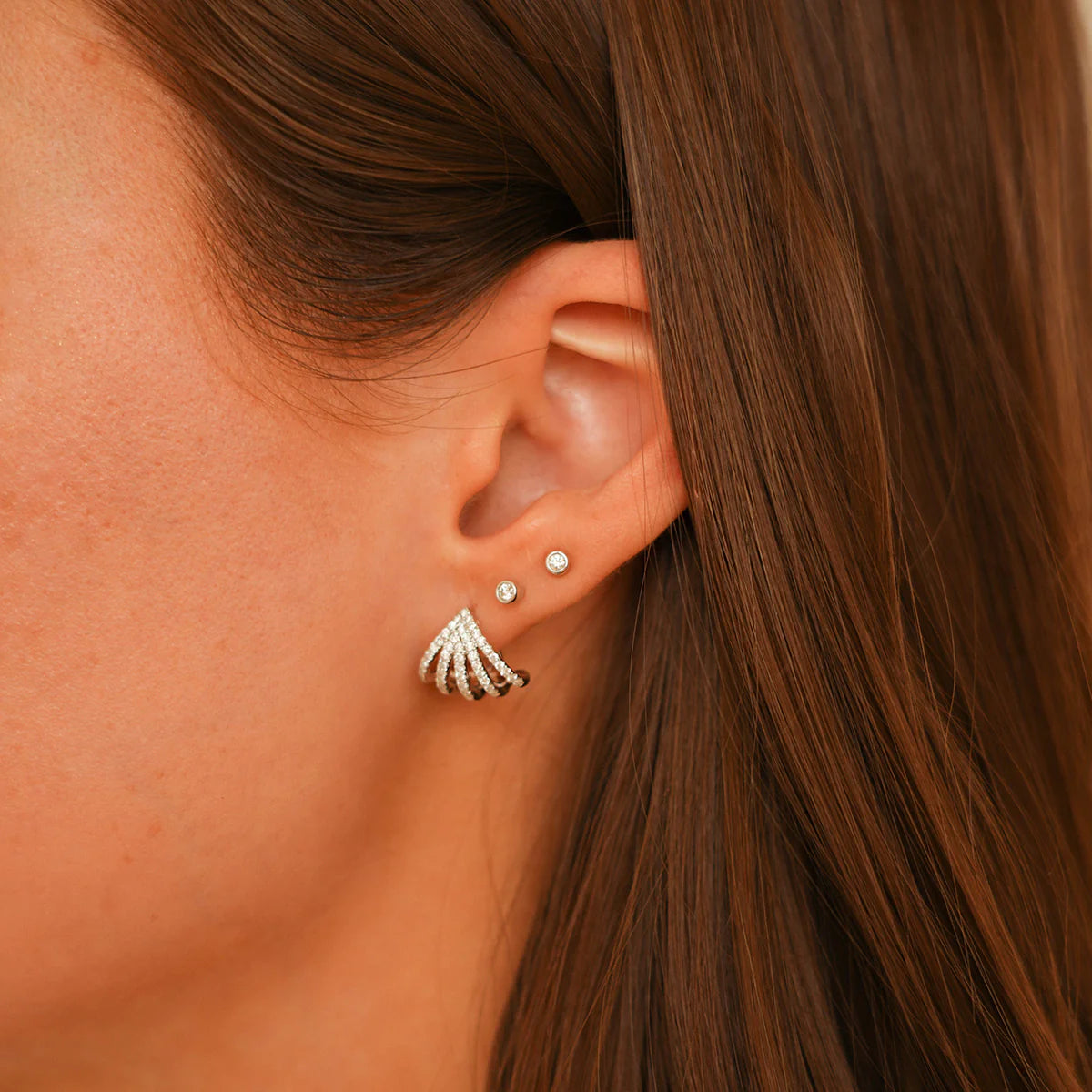 close up of Dana Rebecca Designs Sarah Leah Five Burst Huggies in white Gold stacked with other piercings on model