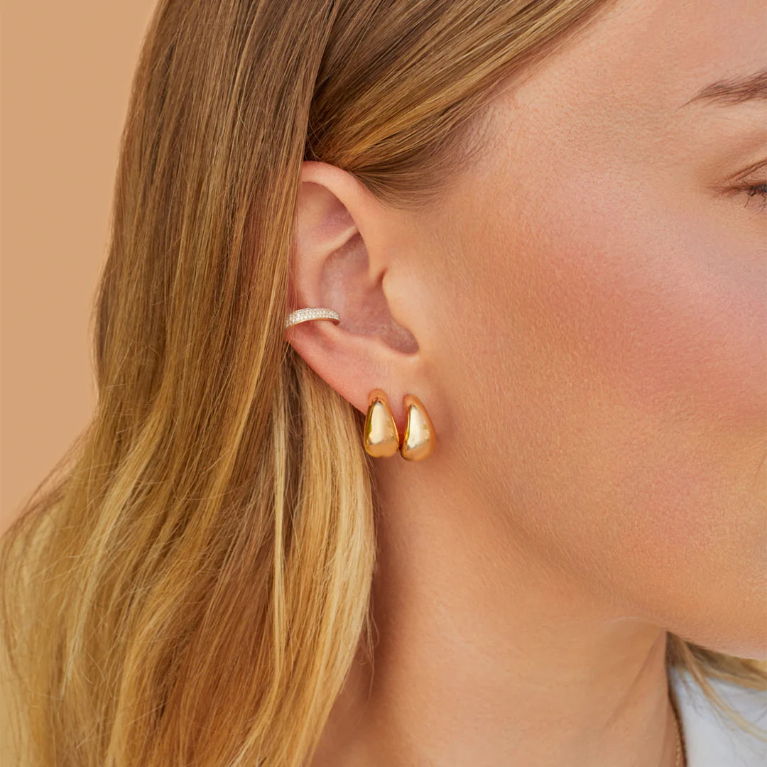 EF-Collection The Gold Jumbo Dome Huggie Earrings in yellow gold styled on models ear with a diamond ear cuff